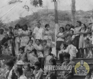 Luego del desastroso terremoto de 1973, un grupo de personas se reúne para reconstruir la iglesia, se observa parte de la barda derrumbada y al fondo los cimientos del nuevo campanario.