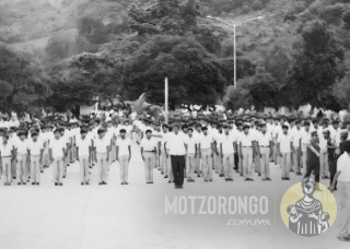 Alumnos de la Secundaria Técnica durante un desfile, en la explanada del parque "Carlos A. Pacheco", se observan los antiguos árboles y el anterior alumbrado del parque.