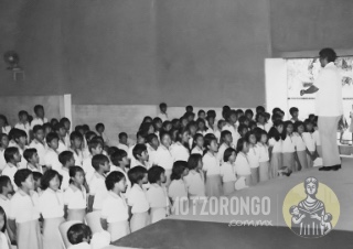 Alumnos de la Secundaria Técnica en el interior del cine "7 de Mayo" entonando probablemente el himno a las escuelas secundarias técnicas, con el profesor Jesús Godínez Olmedo al frente.